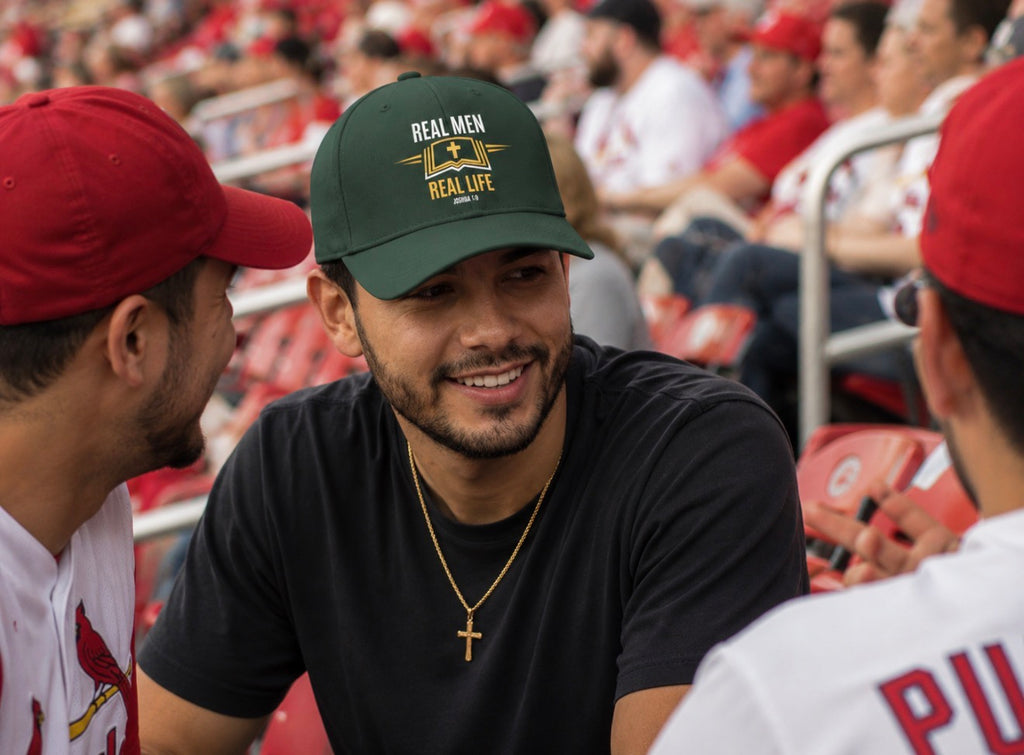 Man wearing RMRL Core Identity Collection evergreen dad cap with gold Real Men Real Life emblem at baseball stadium with friends