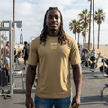 African American man with locs at outdoor beach gym wearing RMRL Coyote Brown Dry-Fit Tee with Real Men Real Life left-chest logo