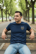 Man relaxing outdoors in park wearing navy RMRL Core Identity Collection tee with bold center-chest Real Men Real Life logo
